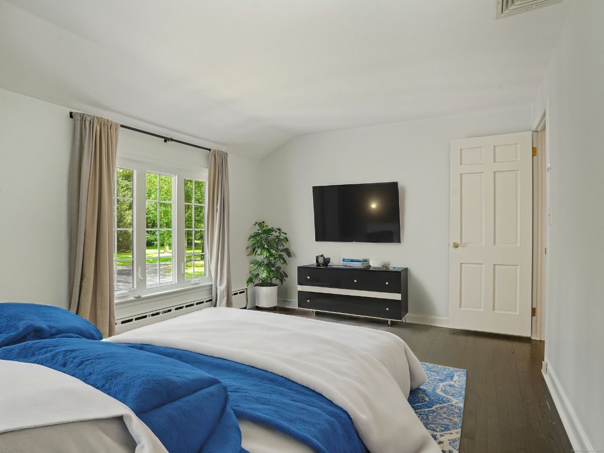 Cozy bedroom with a wall-mounted TV, large window, and vibrant blue bedding.