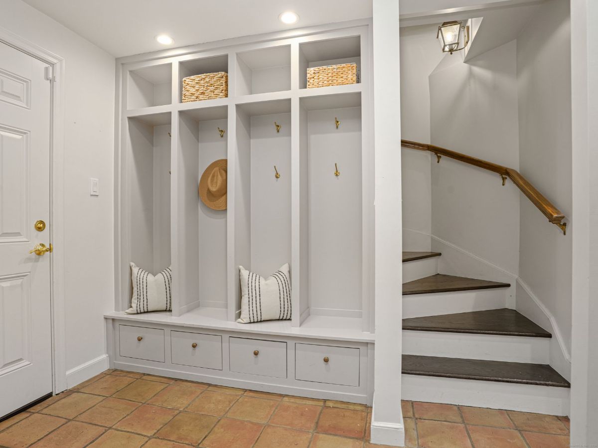 Functional mudroom with built-in storage, coat hooks, and a staircase leading upstairs.