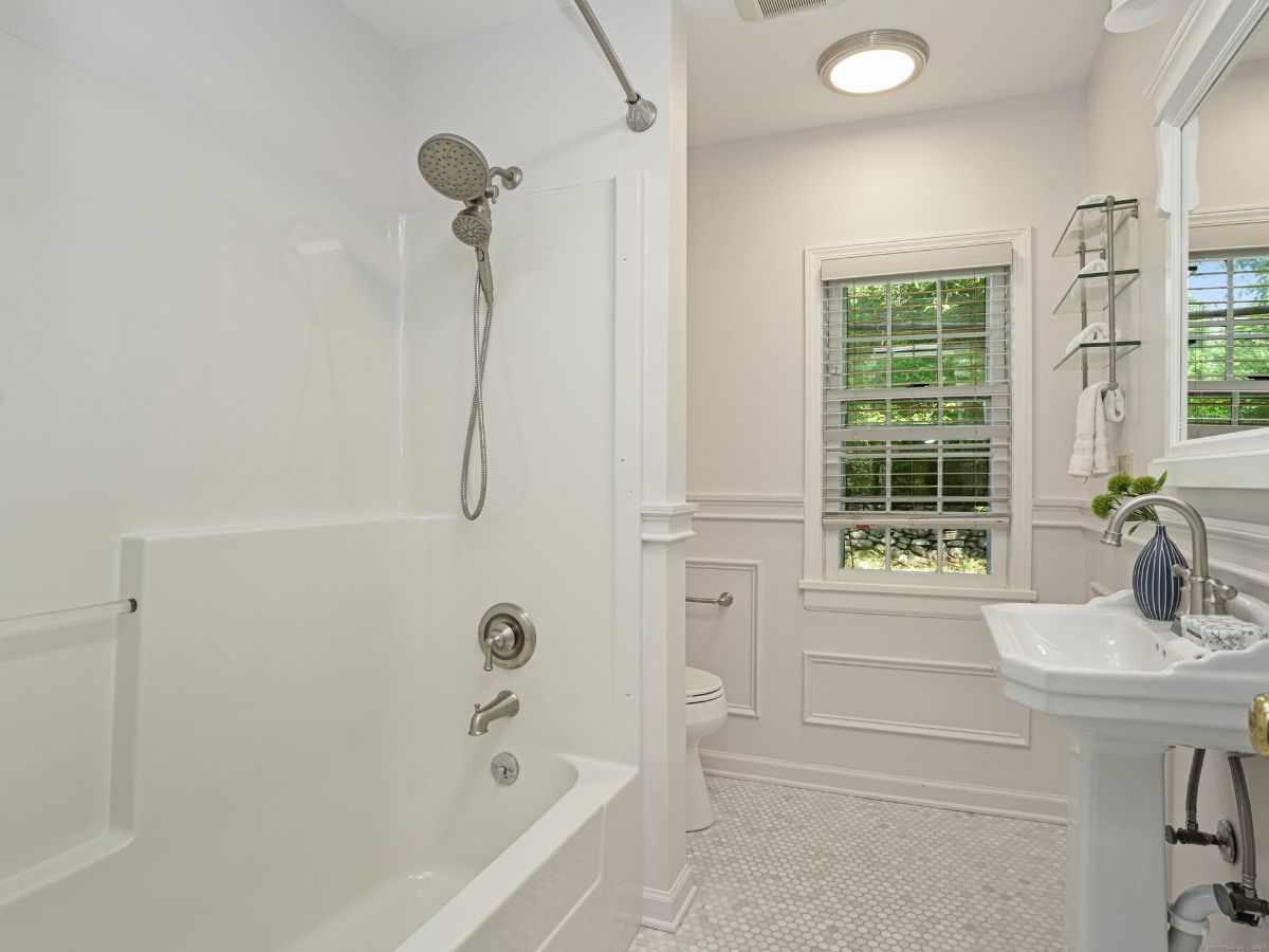 Charming bathroom with a tiled floor, pedestal sink, and modern showerhead.