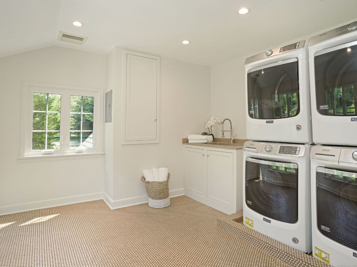 Laundry room with stacked appliances, a utility sink, and a charming window.