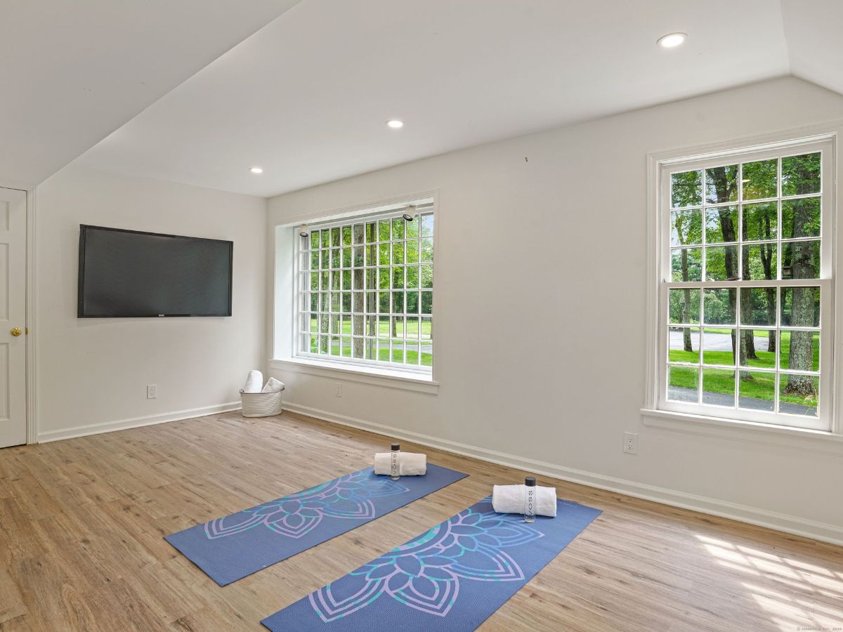 Peaceful yoga room with large windows, wood flooring, and a wall-mounted TV.