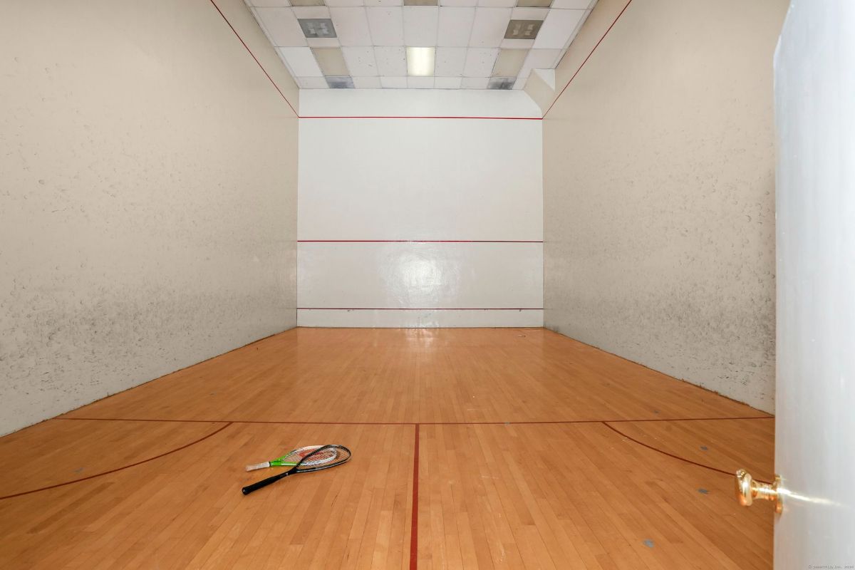 Indoor squash court with polished wood flooring and high walls.