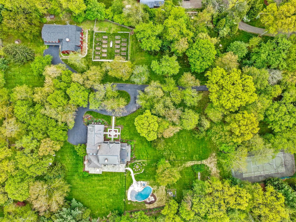 Aerial view of house with pool, and tennis court.