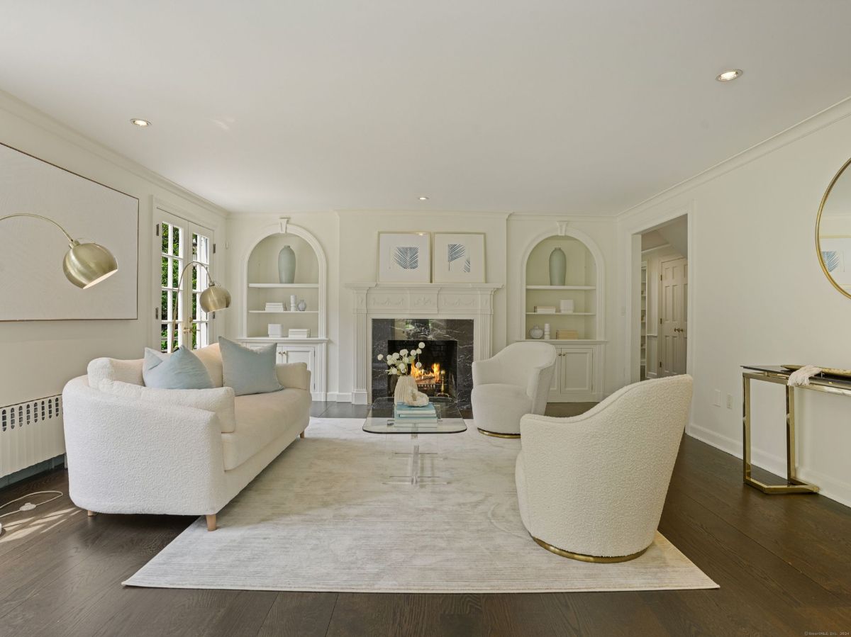 Bright living room with white furniture, a fireplace, and built-in shelving.