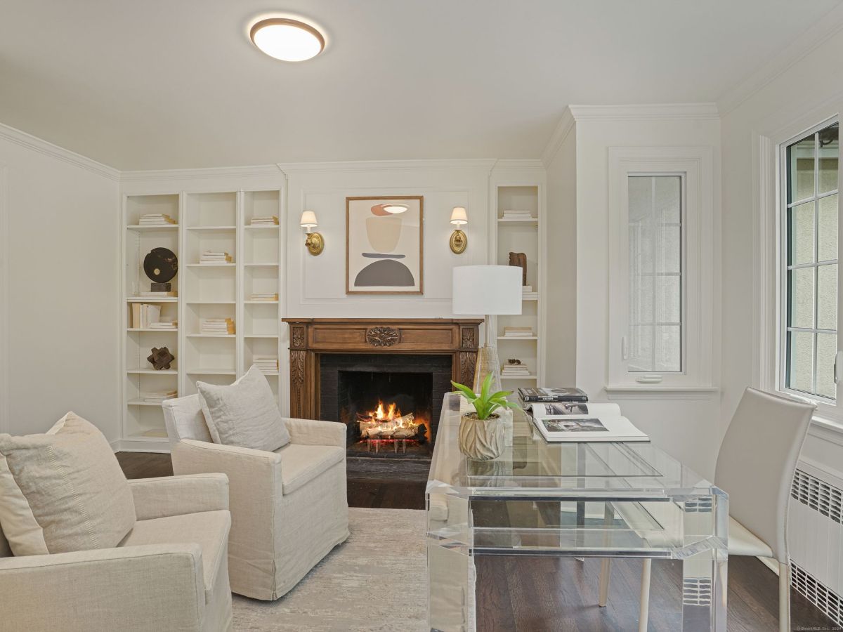 Cozy workspace featuring a fireplace, built-in shelves, and a clear acrylic desk.