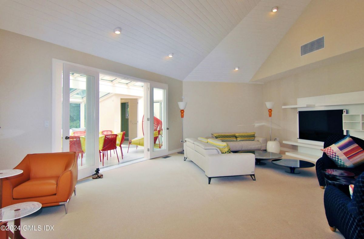 Living area transitions seamlessly into a vibrant sunroom, showcasing modern furnishings and colorful accents.