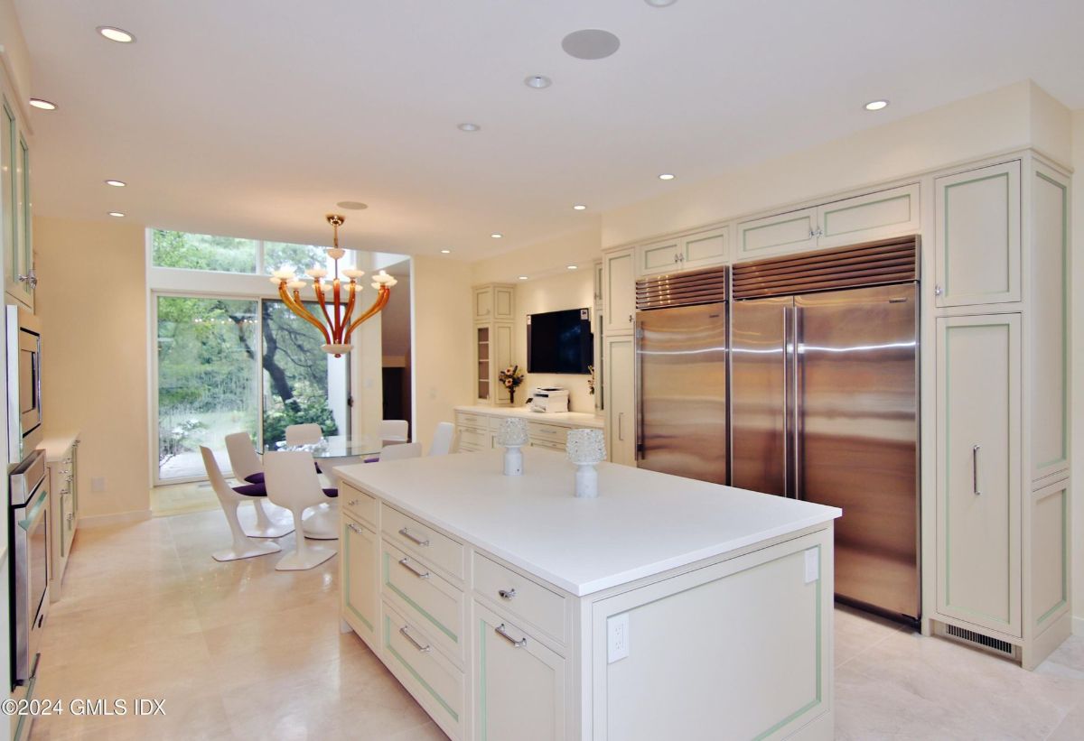 Kitchen connects seamlessly to the dining area, offering views of the lush greenery through large windows.