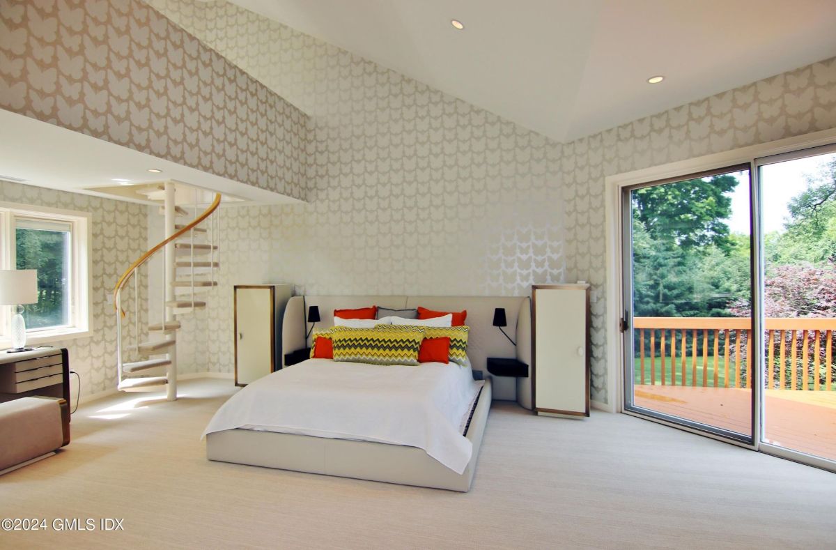 A luxurious bedroom offers access to a private balcony, highlighted by a unique spiral staircase leading to a cozy loft space.