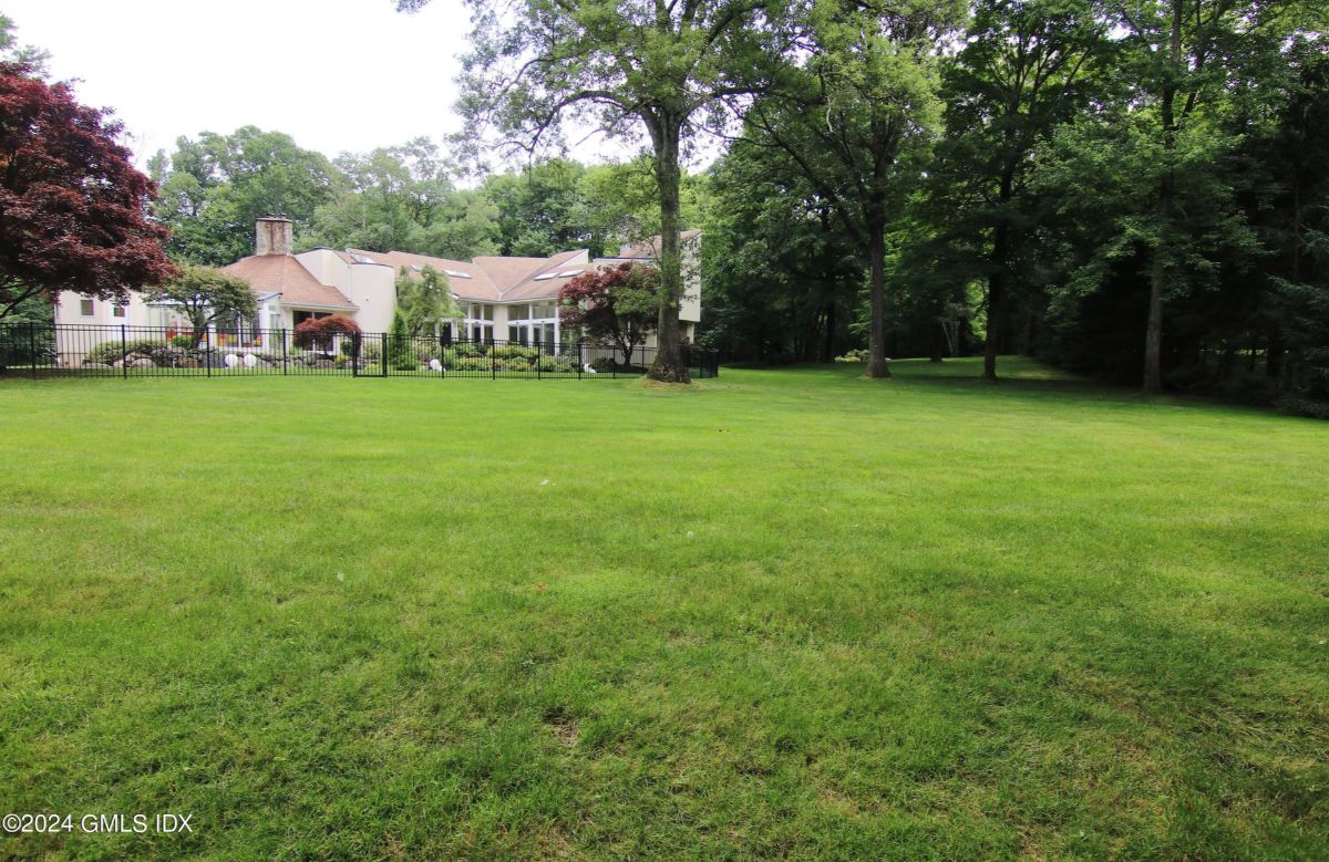 Vast open lawn offers a serene space surrounded by mature trees and private fencing.