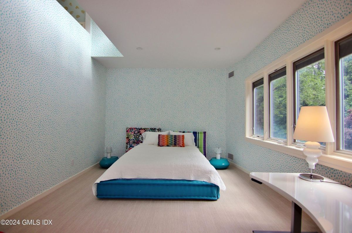 A vibrant bedroom features a patterned accent wall and colorful headboard.