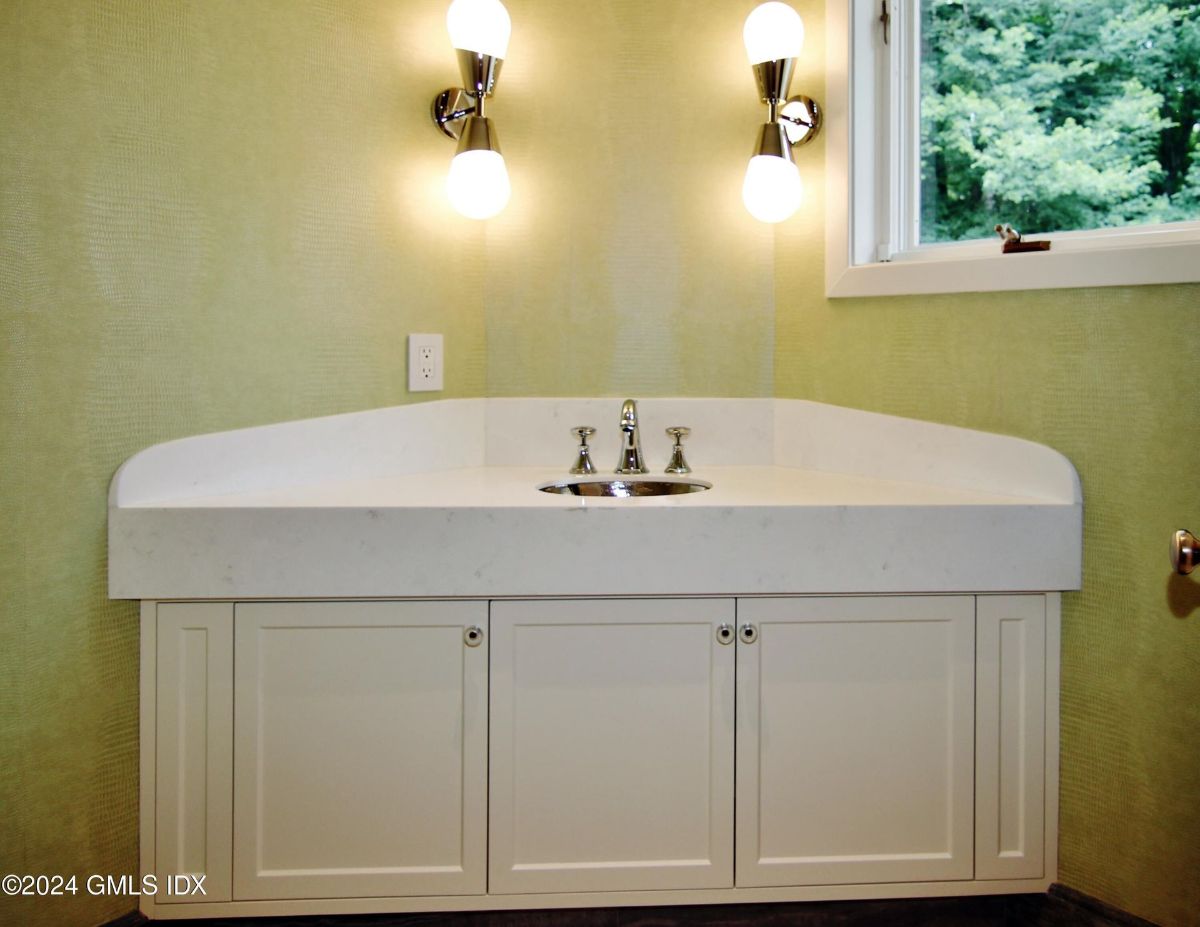 Vanity area showcases a curved countertop, modern lighting fixtures, and a window with scenic outdoor views.