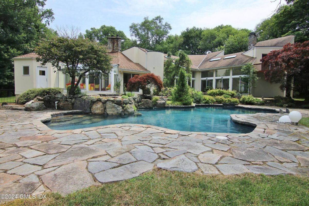 Stone pathways encircle a serene pool, complementing the architectural elegance of the estate.