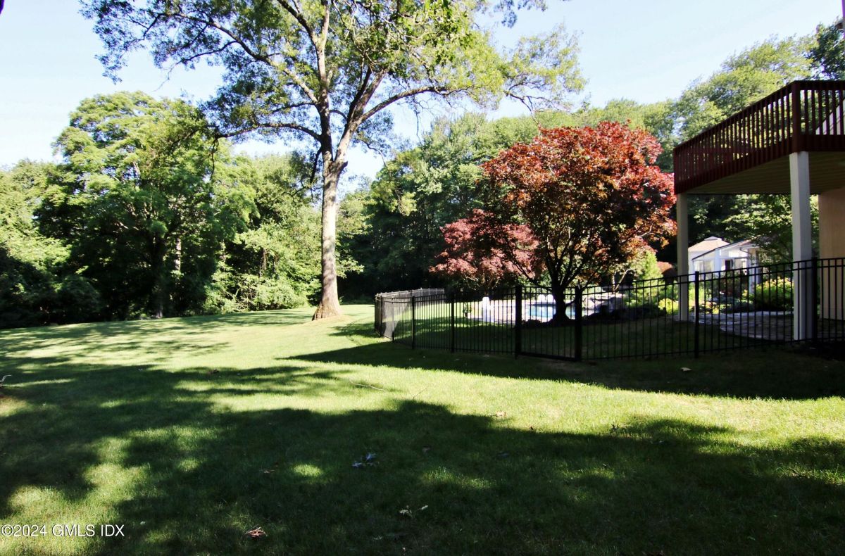 Lush greenery and mature trees create a peaceful outdoor retreat with a fenced-in area ideal for relaxation or recreation.