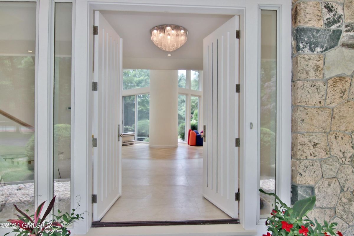 Grand double doors open to reveal a bright and spacious interior with expansive windows that frame lush outdoor views.