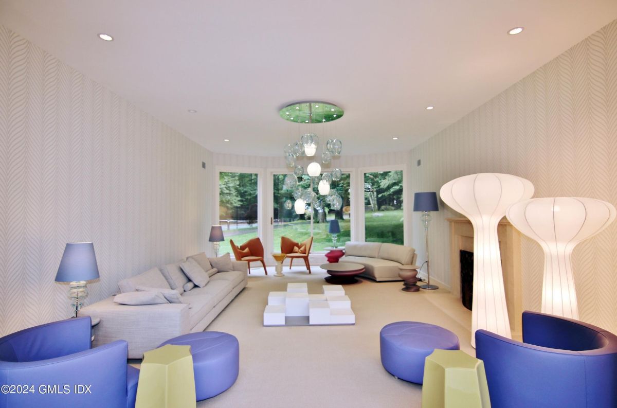 A spacious living room bathed in natural light showcases vibrant seating and a statement chandelier, blending comfort with modern elegance.