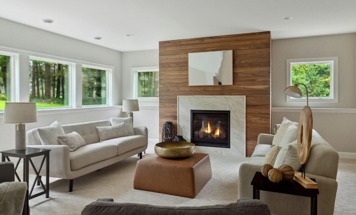 Natural light floods this cozy living space featuring a modern gas fireplace with a wood-accented wall and stone surround.