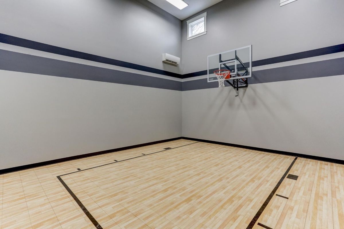 An indoor basketball court with polished hardwood flooring and a wall-mounted hoop.