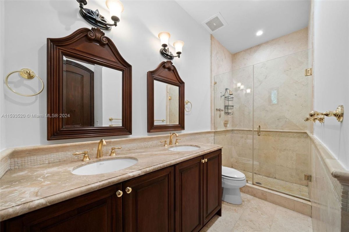 Double vanity bathroom with wood cabinetry and marble countertops.