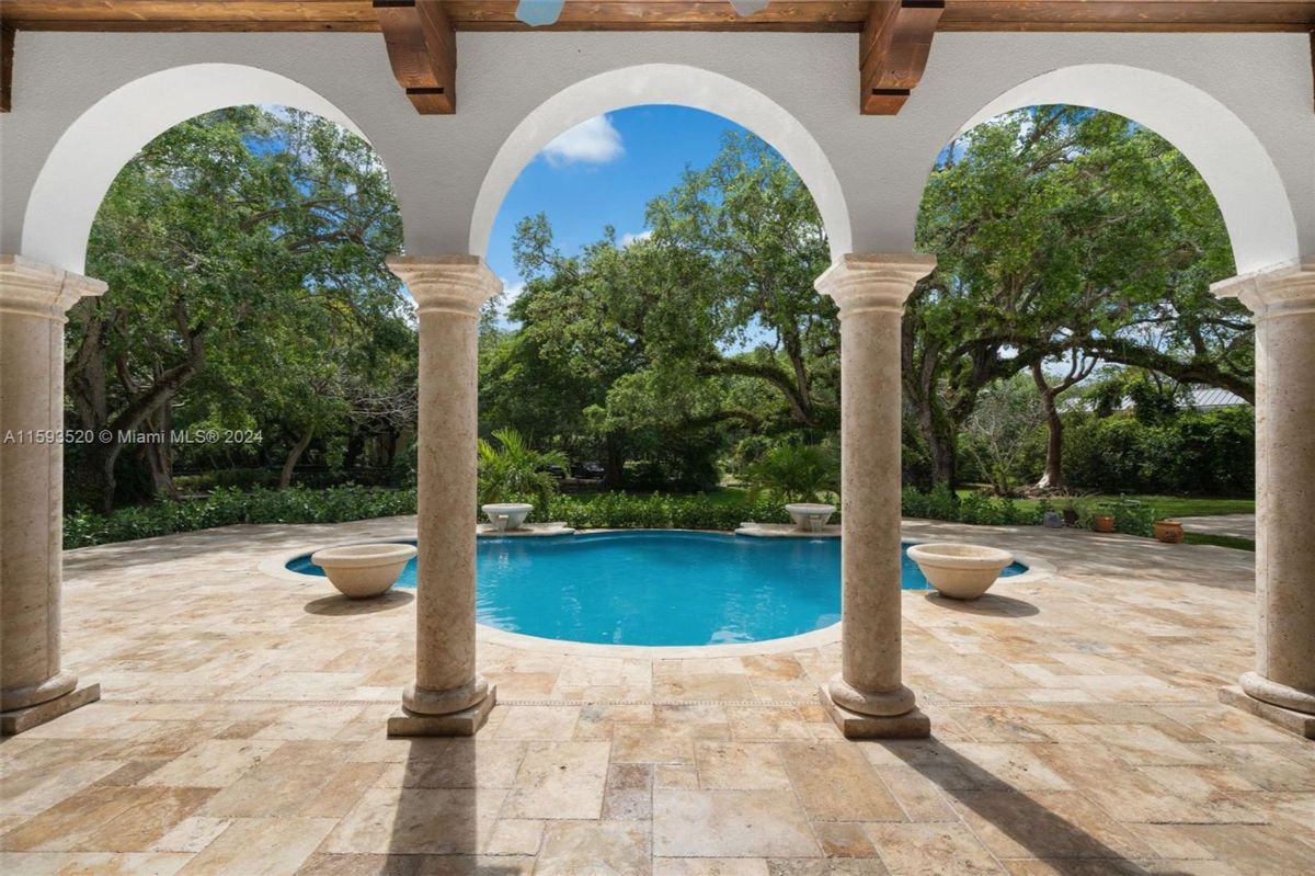 Framed poolside view with elegant stone columns and lush greenery surrounding the serene setting.