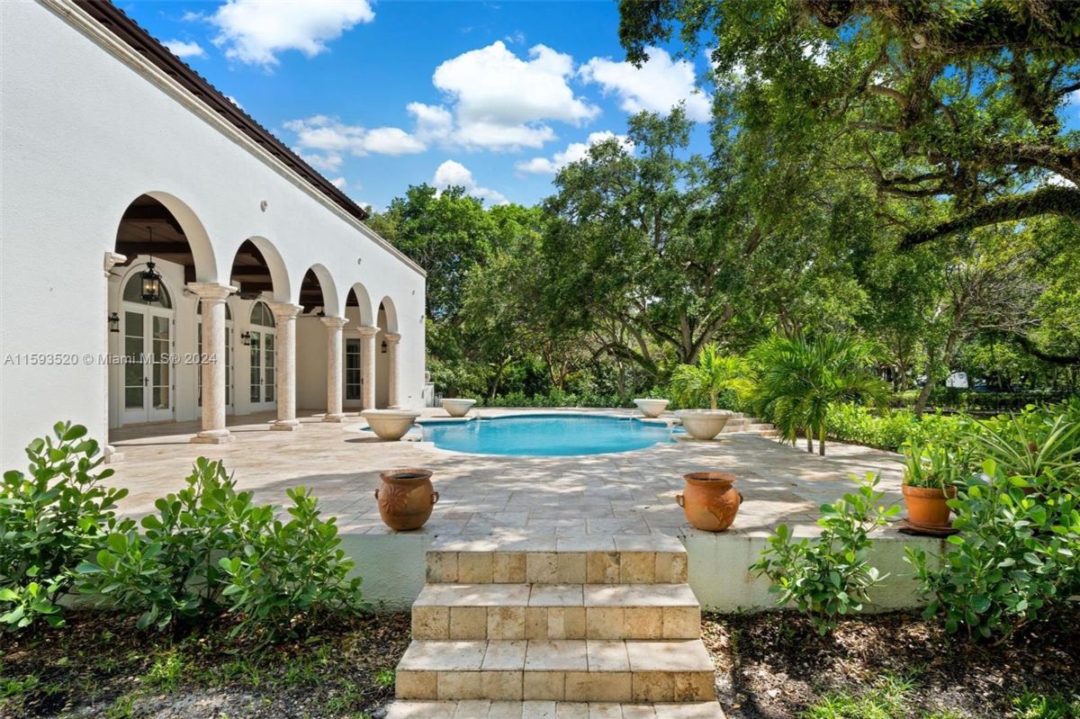 Poolside terrace framed by lush greenery and arched architecture.