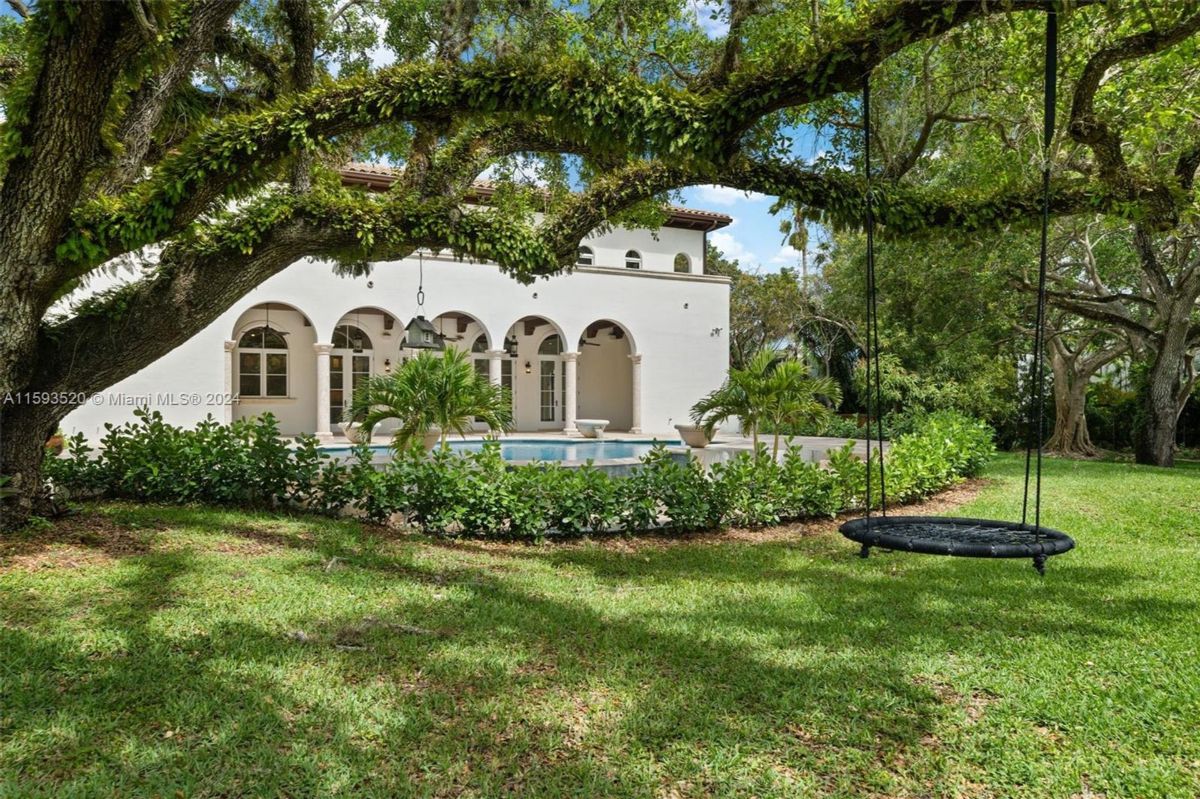 Arched columns frame a view of the pool surrounded by lush greenery.