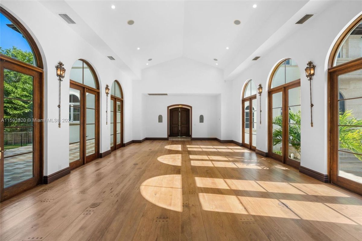 Bright sunlit room featuring elegant arched windows and warm hardwood flooring.