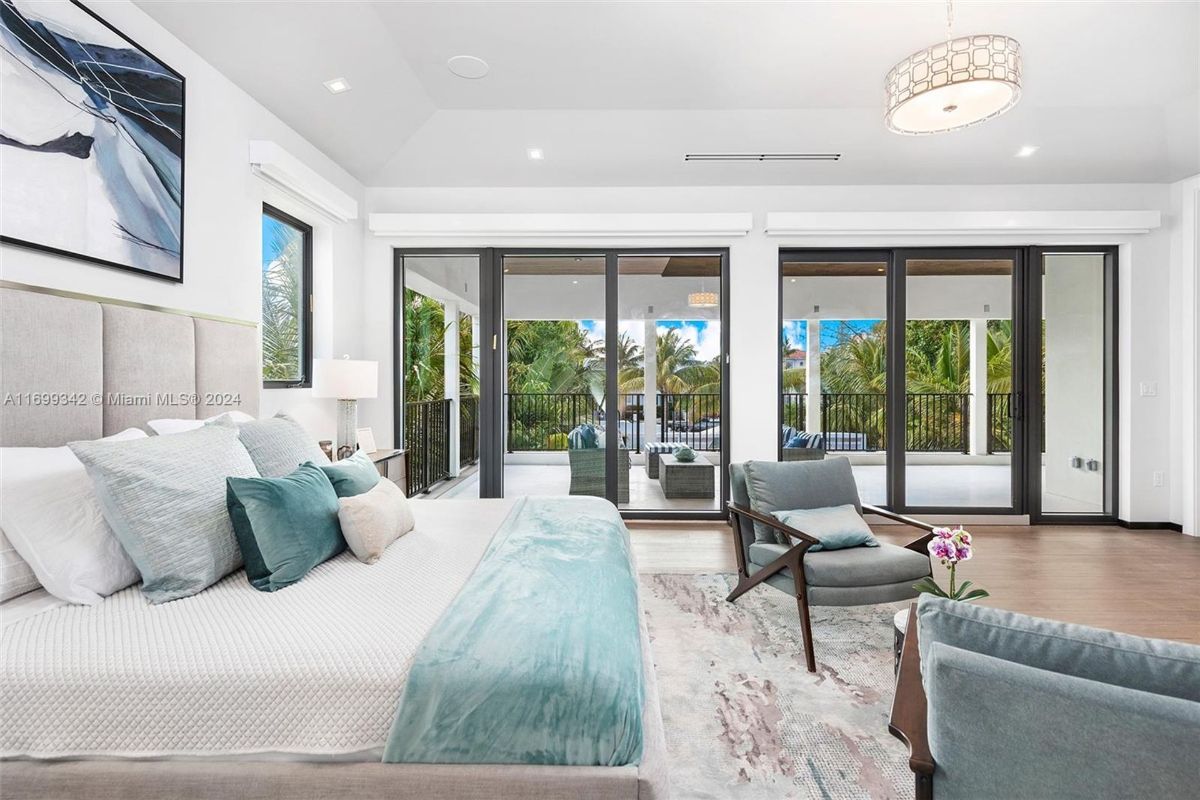 Bedroom blends elegant design with natural light, offering seamless access to a private balcony overlooking tropical greenery.