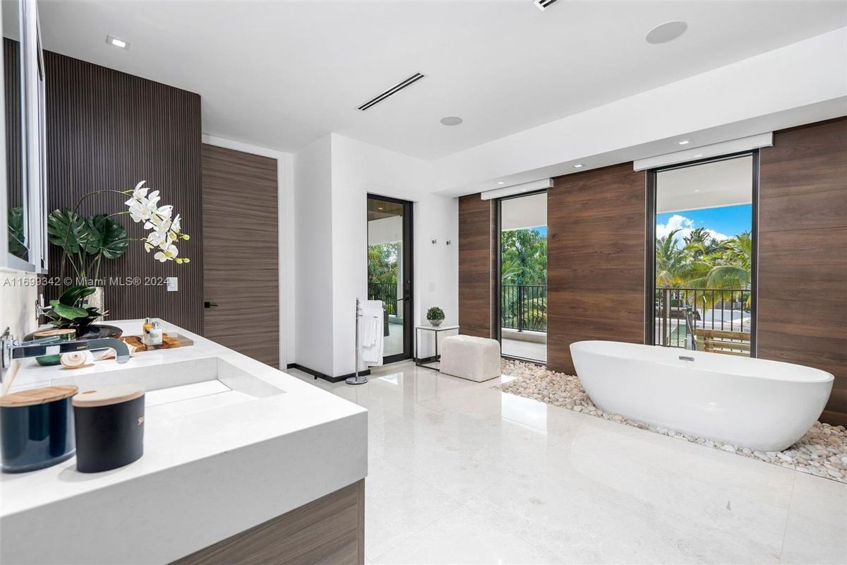 Bathroom featuring a freestanding tub, wooden accent walls, and balcony views.