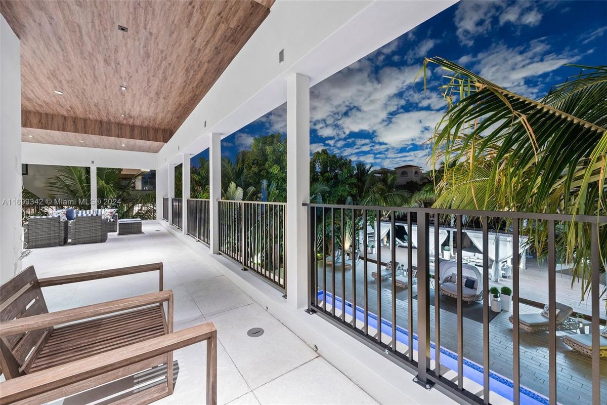 Covered balcony overlooking the pool and lush tropical landscape.