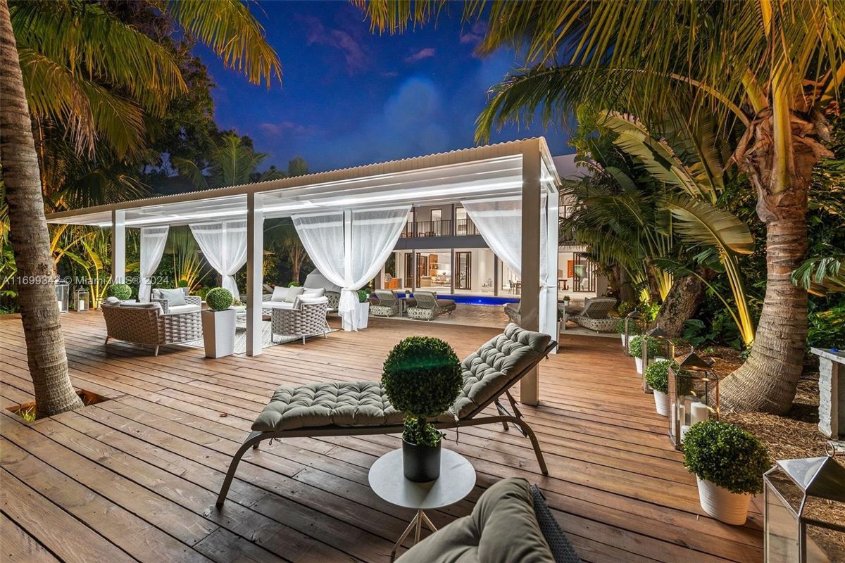 Elegant poolside pergola with flowing white curtains and lush tropical surroundings.