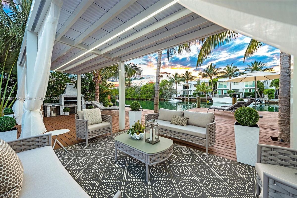 Stylish outdoor lounge overlooking serene waterfront views, surrounded by palm trees and modern accents.