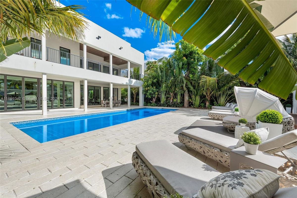 A sparkling pool surrounded by tropical greenery and elegant loungers under the sun.