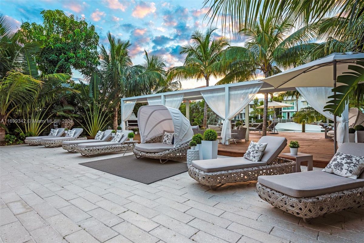 Elegant poolside seating with modern loungers and a shaded cabana framed by lush tropical greenery.