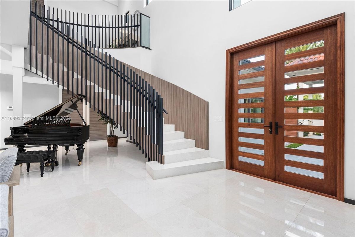 Grand piano gracefully positioned beneath a contemporary spiral staircase with sleek wooden accents and iron balusters.