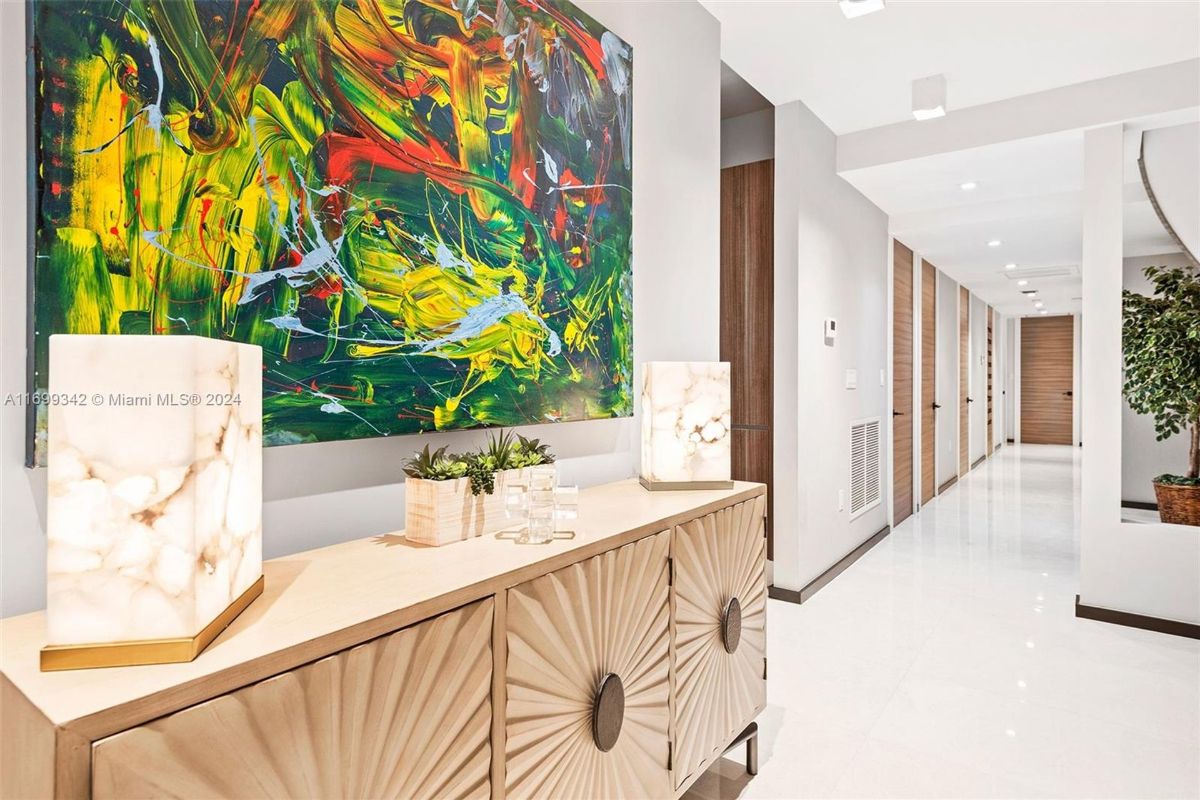 Vibrant abstract artwork adds a pop of color to the modern hallway, complemented by a textured console and marble-inspired lamps.