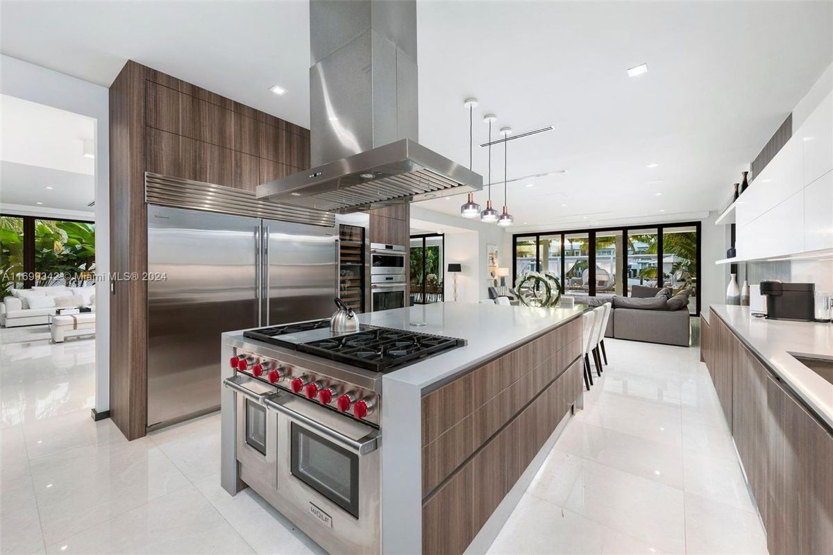 Kitchen featuring a central island with a stainless steel cooktop, pendant lighting, and seamless integration of appliances.