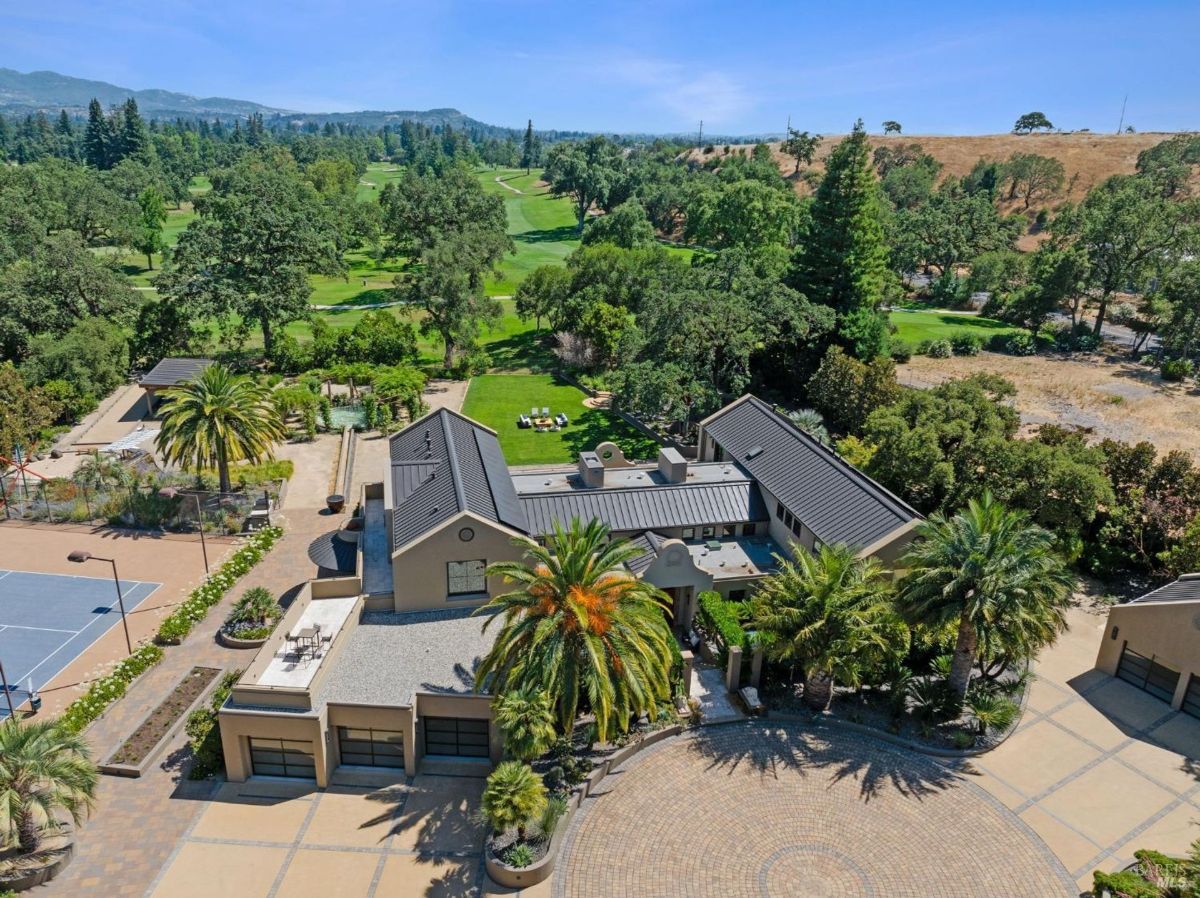 Expansive estate with lush landscaping, tennis court, and golf course views.