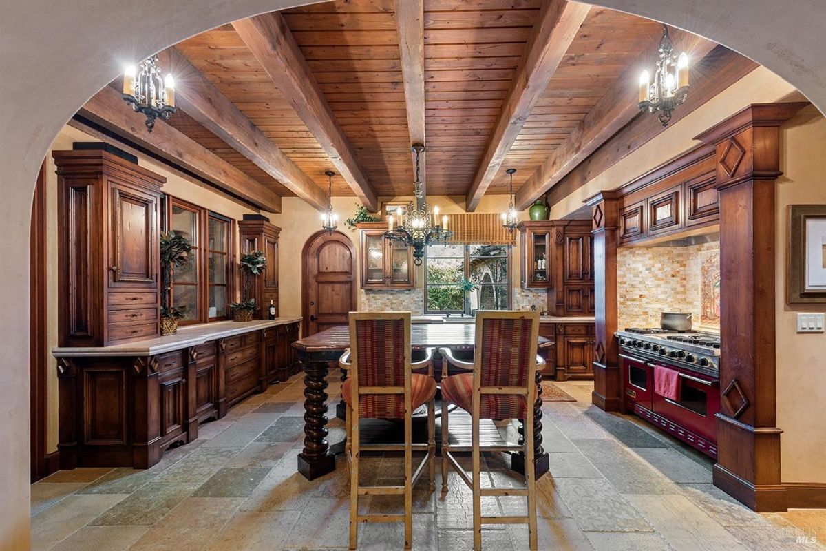 Rustic kitchen design featuring exposed wood beams, custom cabinetry, and a bold red stove.