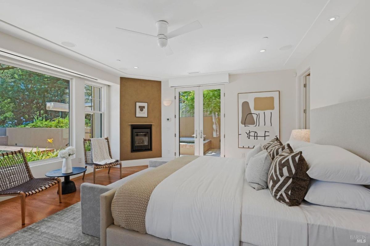 Serene bedroom with natural light, a cozy fireplace, and private patio access.