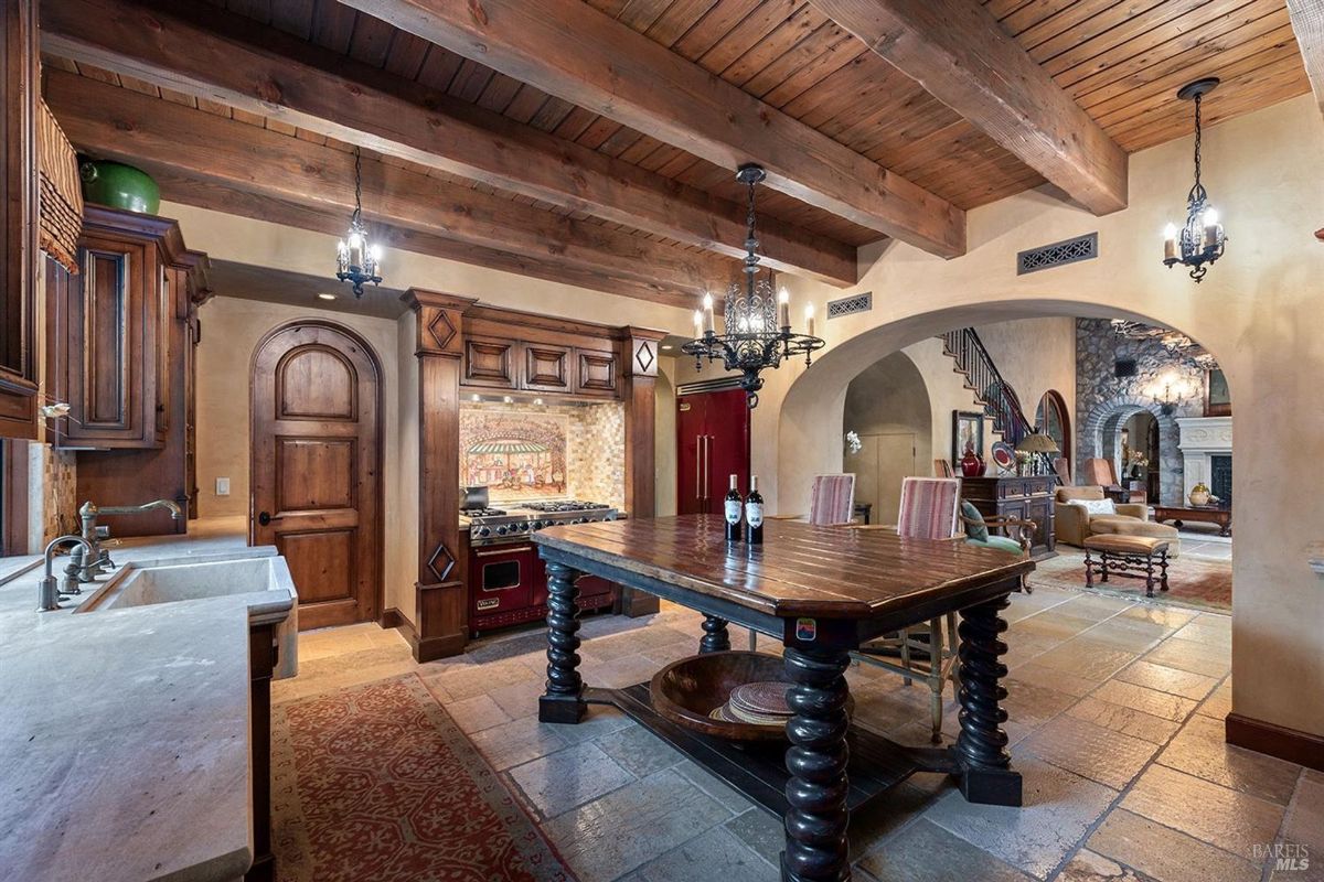 Kitchen with exposed wood beams, custom cabinetry, and a central farmhouse table.