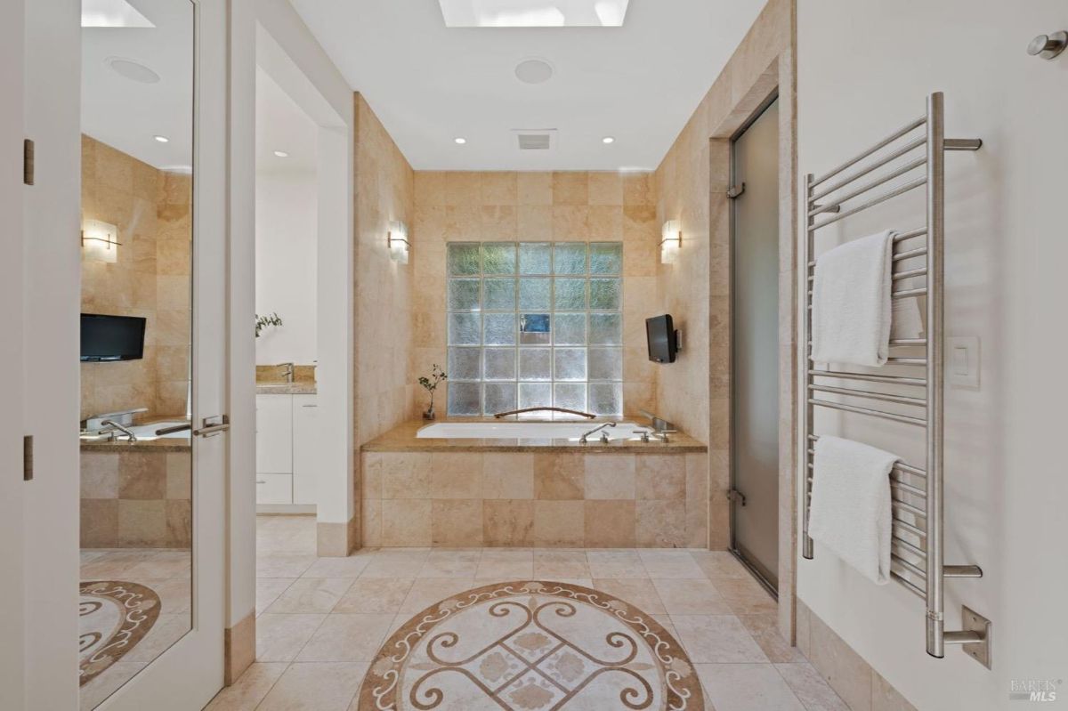 Spa-like bathroom featuring a soaking tub, glass block window, and warm tiled walls.