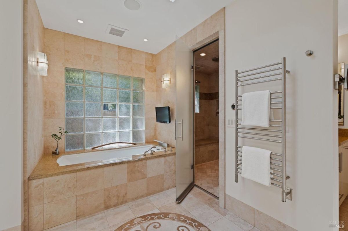 Luxurious bathroom showcasing a soaking tub, glass block window, and an adjacent walk-in shower.