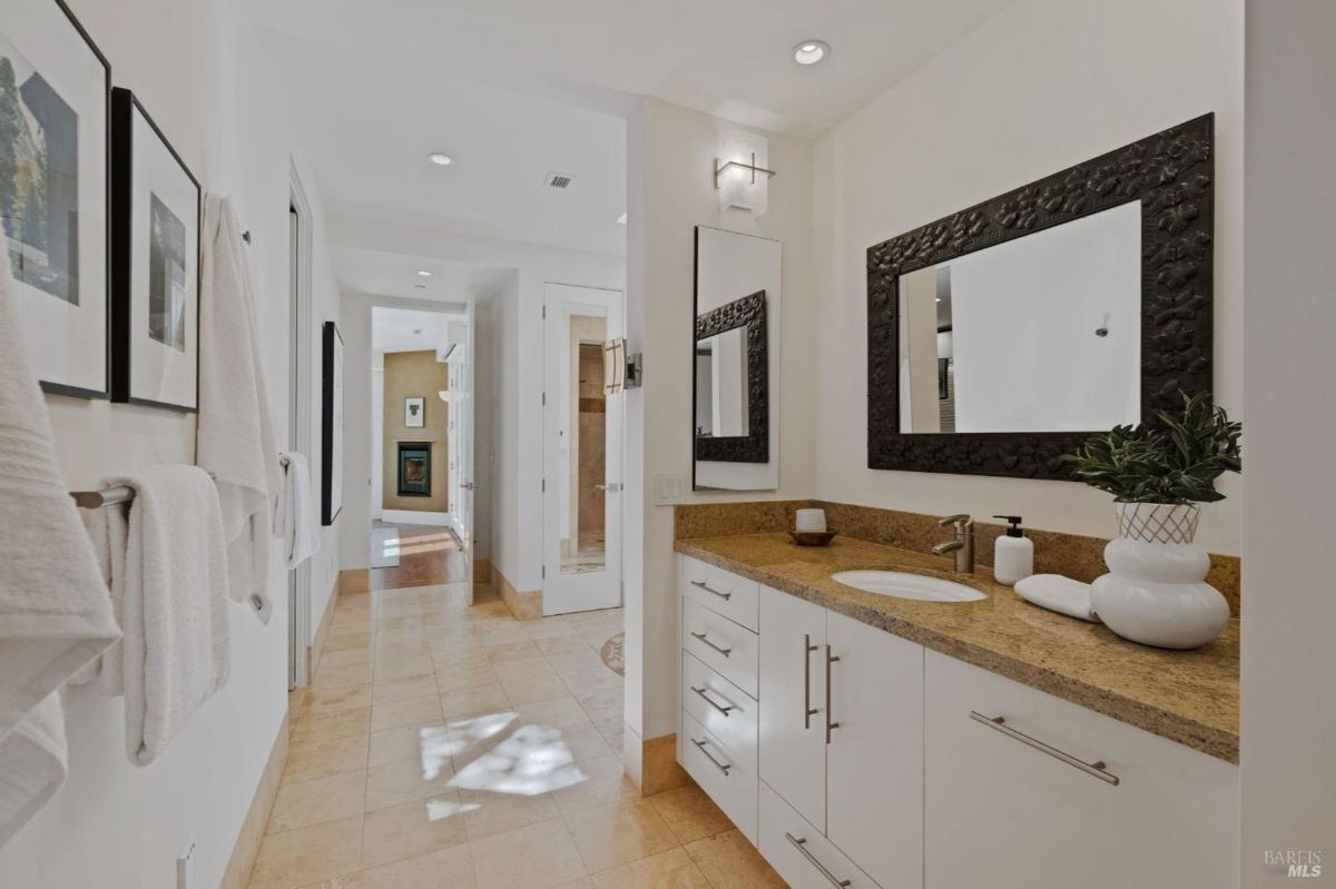 Bathroom featuring a granite countertop with a modern sink and textured mirror accents.