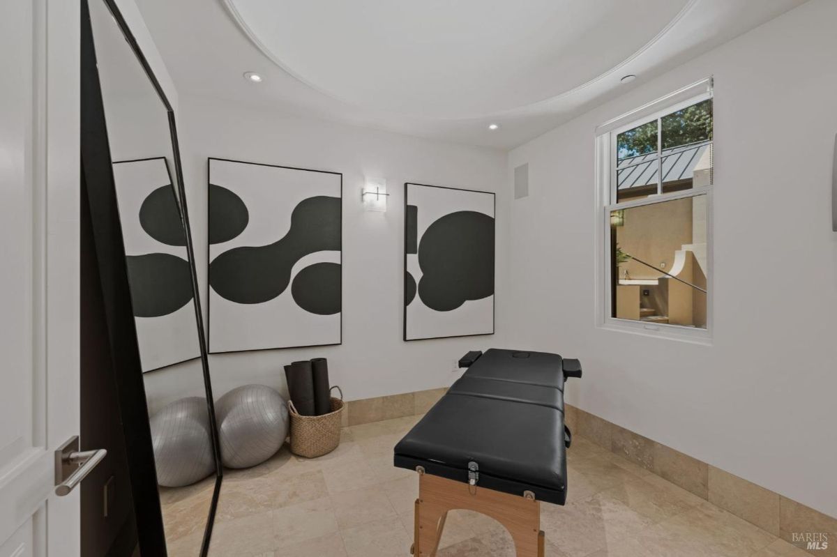 A serene wellness room featuring a massage table, minimalist artwork, and natural light.