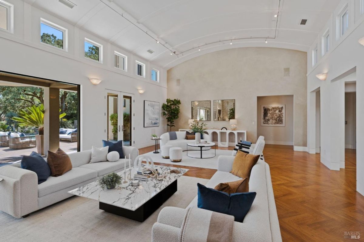 Bright living area with soaring ceilings, large windows, and elegant contemporary furnishings.