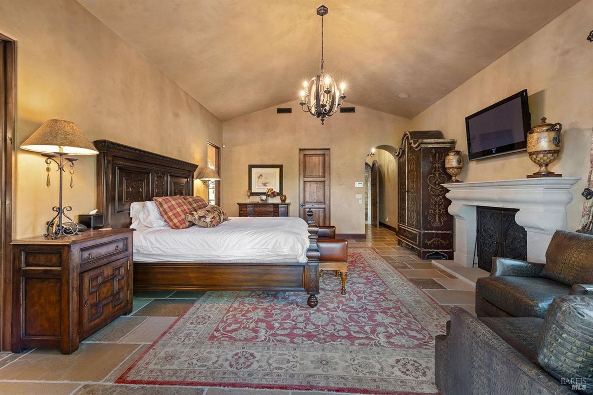 Bedroom featuring a vaulted ceiling, ornate furnishings, and a cozy fireplace.