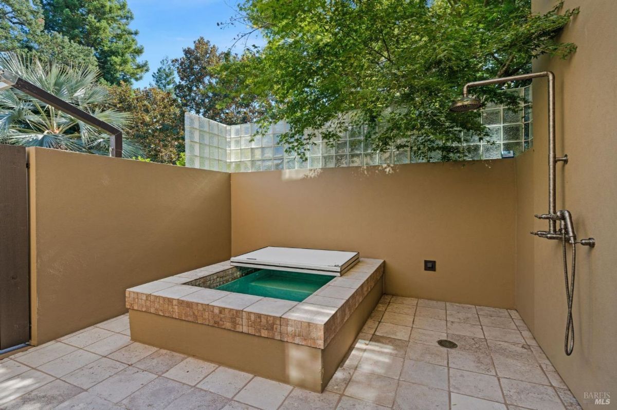 A private outdoor spa retreat with a soaking tub and open-air shower, surrounded by lush greenery.