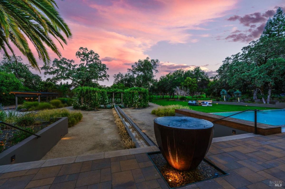 Peaceful garden with lush greenery, a flowing water feature, and vibrant sunset hues offers a serene outdoor retreat.