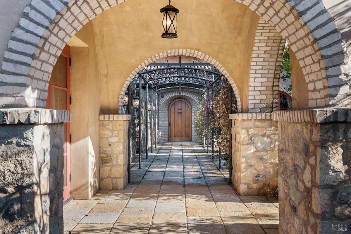 Stone archways lead to a charming wooden door framed by climbing vines.