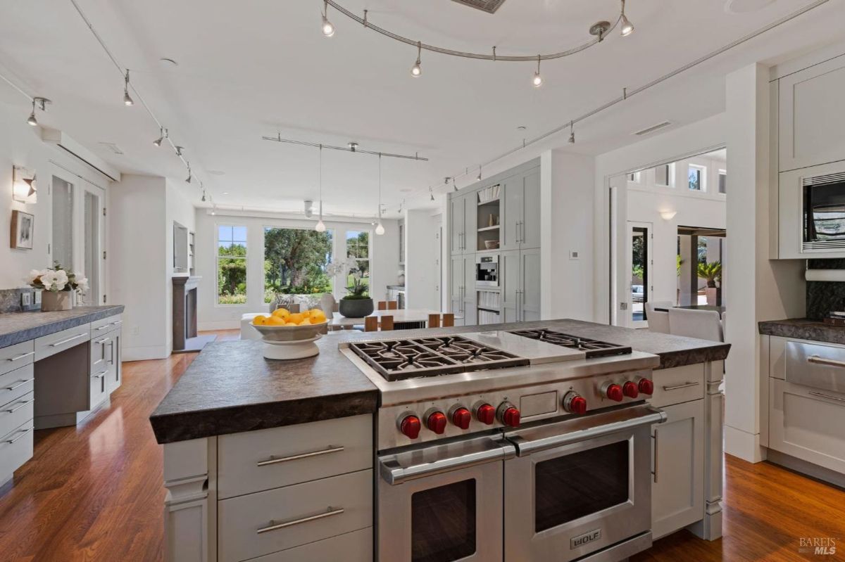 Modern kitchen featuring high-end Wolf appliances, sleek countertops, and open access to living spaces.